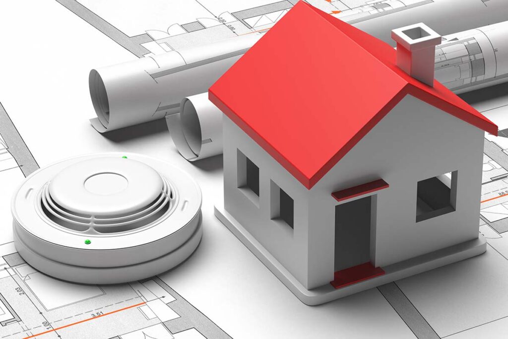 Smoke detector and small house on blueprint drawing background.
